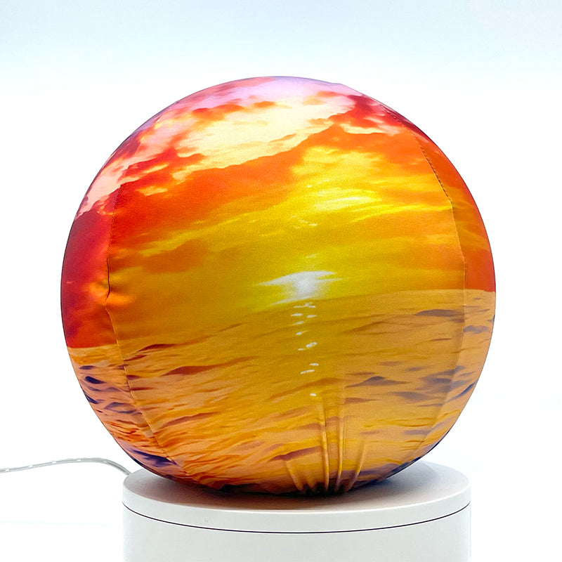 Fabric sphere cover featuring an ocean sunset design, wrapped around a 8.7" soccer ball, 9.5" basketball ball, or a 10" globe.