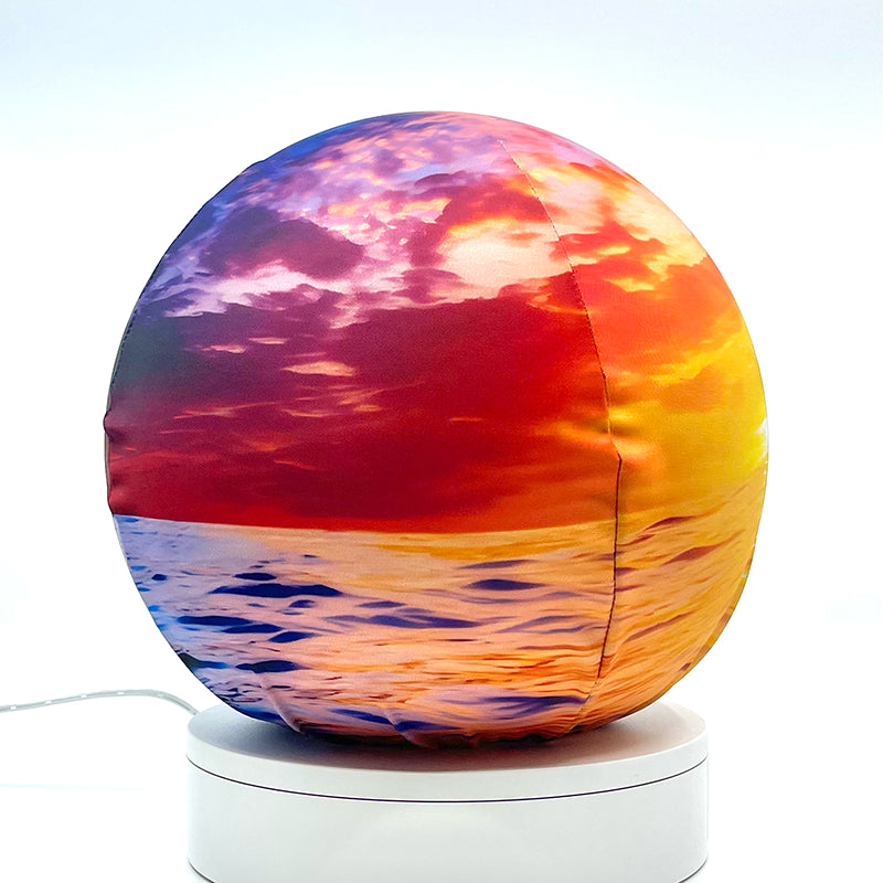 Fabric sphere cover featuring an ocean sunset design, wrapped around a 8.7" soccer ball, 9.5" basketball ball, or a 10" globe.