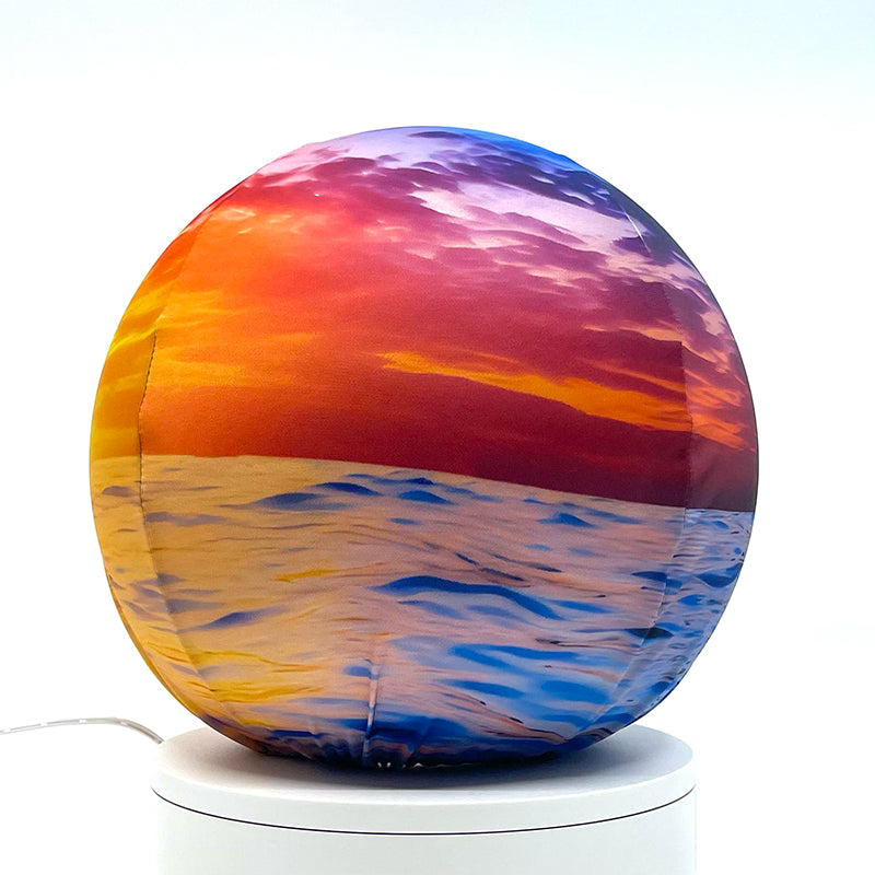 Fabric sphere cover featuring an ocean sunset design, wrapped around a 8.7" soccer ball, 9.5" basketball ball, or a 10" globe.